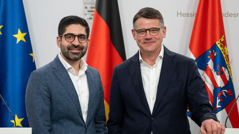 Wirtschaftsminister Kaweh Mansoori und Ministerpräsident Boris Rhein stehen nebeneinander und schauen in die Kamera für ein Foto