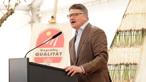 Ministerpräsident Rhein steht an einem Rednerpult und spricht. im Hintergrund ist ein Aufsteller mit Spargel zu sehen und ein Aufsteller "Geprüfte Qualität" mit dem Hessenlöwen.