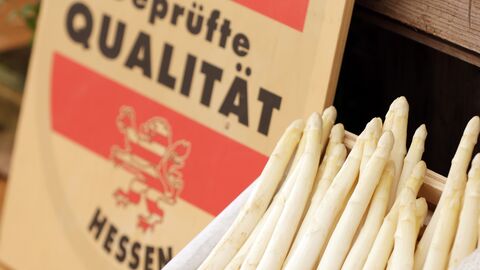 Ein Korb Spargel steht neben dem Schild mit der Aufschrift "Geprüfte Qualität - Hessen".