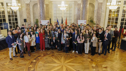 Über 100 Menschen stehen in einem Festsaal nebeneinander.