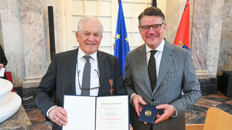 Zwei Männer stehen nebeneinander und halten eine Urkunde hoch.