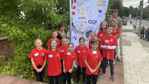 Schülerinnen und Schüler der Gönser Grundschule aus Butzbach hissen die von ihnen gestaltete Fahne zum Thema Kinderrechte gemeinsam mit  der hessischen Staatssekretärin für Soziales und Integration Anne Janz und der hessischen Kinder- und Jugendrechtebeauftragte Miriam Zeleke