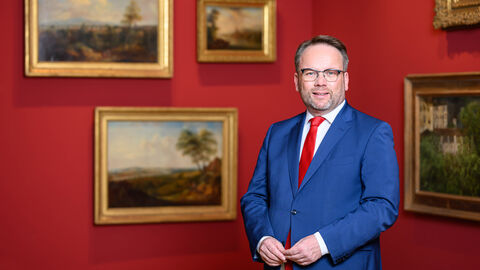 Staatsminister Timon Gremmels vor Gemälden im Museum Wiesbaden